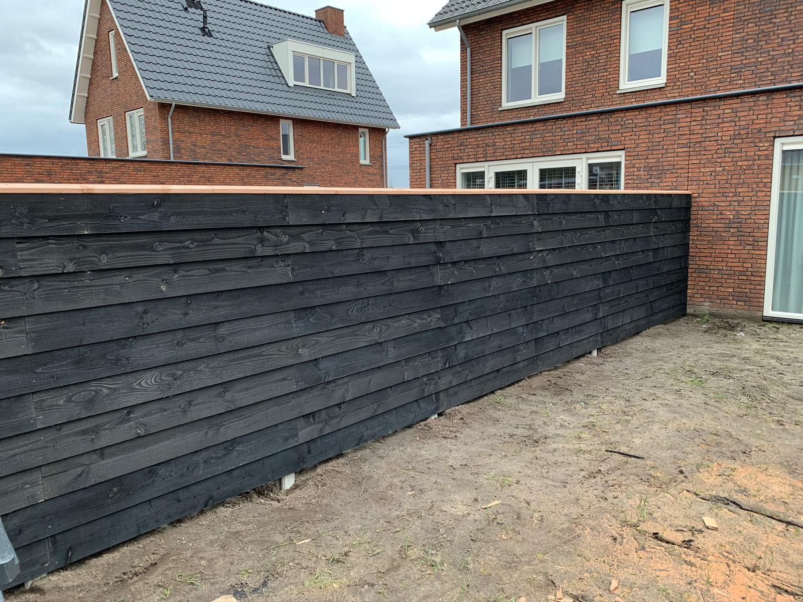 Zwarte horizontale houten schutting met afdekplank